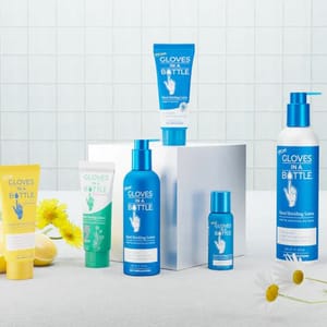 The set includes a variety of \“Gloves In A Bottle\“ hand and foot shielding lotions, featuring blue, green, and yellow packaging with different sizes for diverse skincare needs. The arrangement includes floral accents and a minimalist, clean aesthetic.