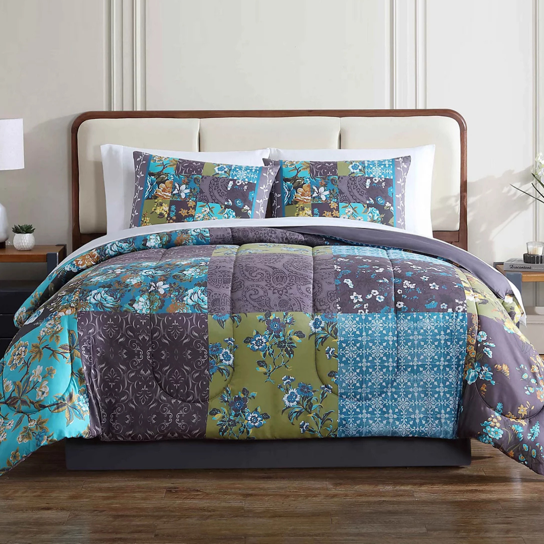 A bedding set with a patchwork design consisting of mixed patterns in shades of blue, brown, and white, including floral and paisley prints, with coordinating pillowcases.