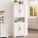 A white kitchen cabinet with four doors, featuring a middle open shelf displaying spices and decor, stands next to a countertop with a coffee maker. There's also a potted plant and a wicker basket on top.
