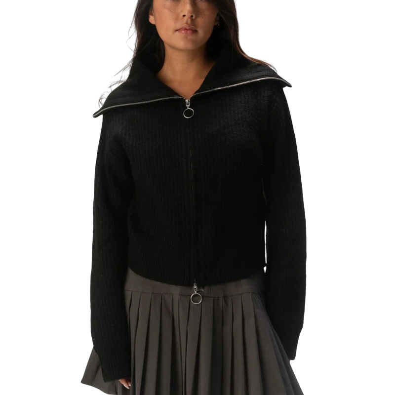 Black zip-up sweater with a wide collar, paired with a gray pleated skirt.