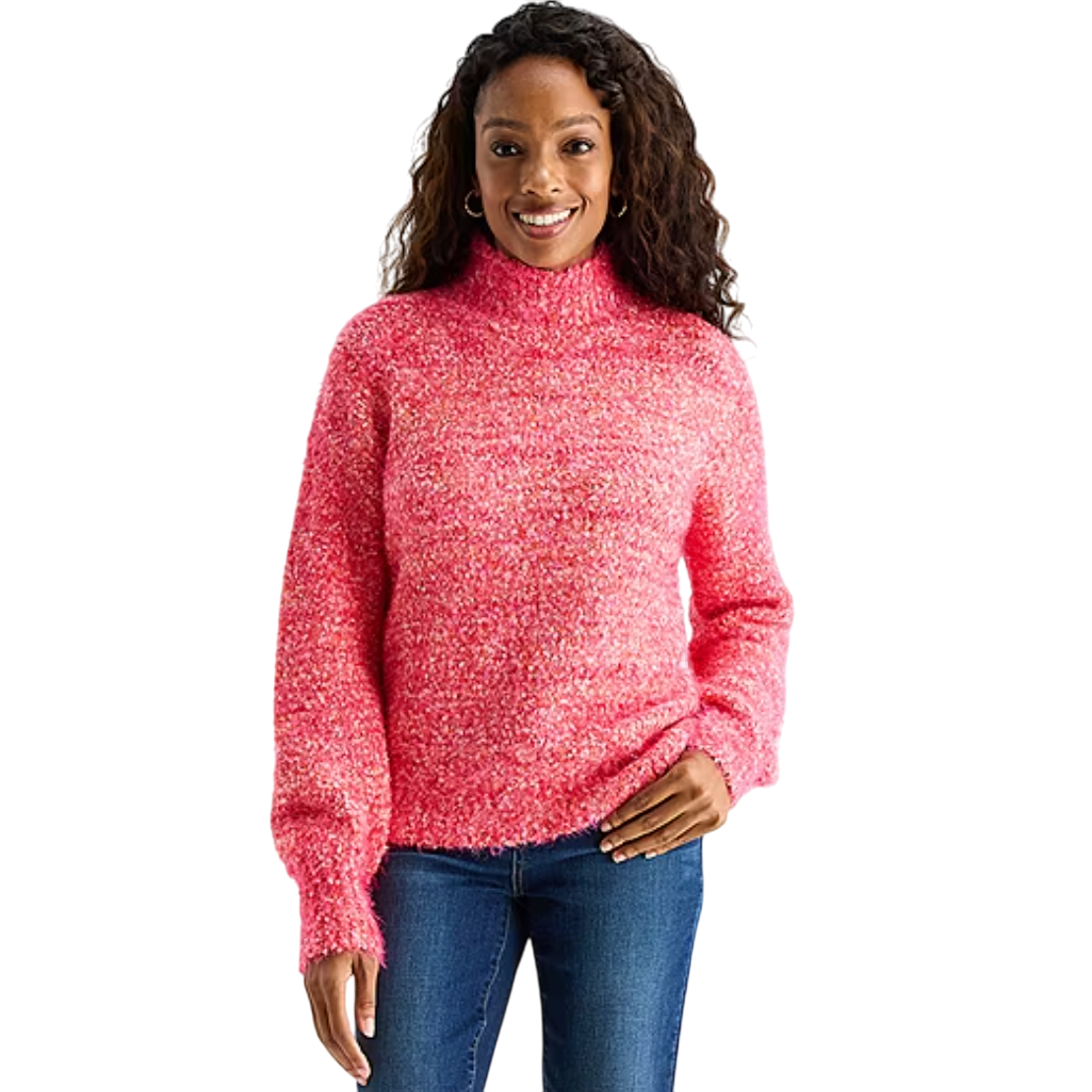 A woman wearing a textured pink turtleneck sweater paired with blue jeans, standing and smiling.