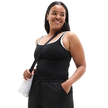 A person is wearing a black tank top with white trim, black pants, and carrying a white bag with a black strap.