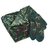 A folded blanket and a pair of socks with a festive green and red holly pattern.