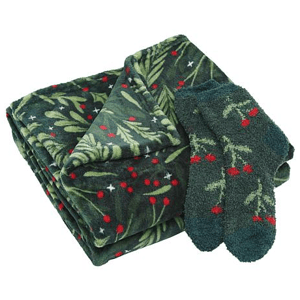 A folded blanket and a pair of socks with a festive green and red holly pattern.