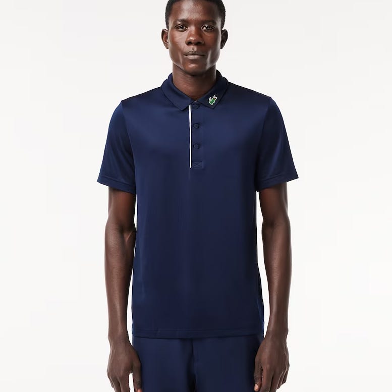 A man is wearing a navy blue polo shirt with a small green emblem on the chest.