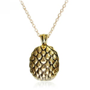 Gold-toned pendant necklace featuring a textured design resembling a dragon egg, suspended on an 18-inch chain.