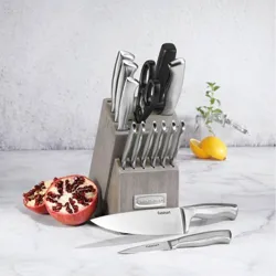 A Cuisinart knife set displayed in a wooden block includes a variety of knives and kitchen shears, with a halved pomegranate and a lemon in the background on a marble surface.