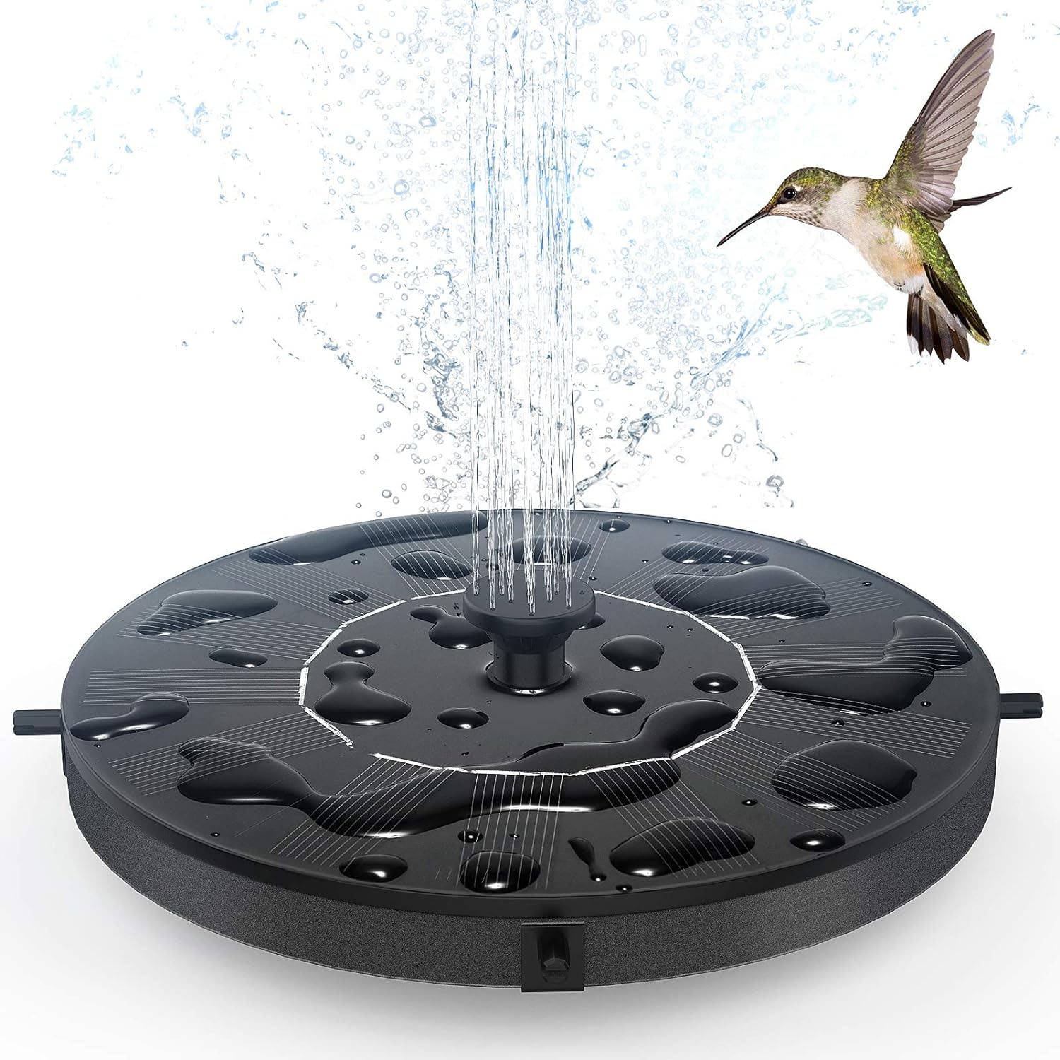 A round, black solar-powered birdbath fountain featuring a central water spout creating vertical jets, and a hummingbird hovering nearby.