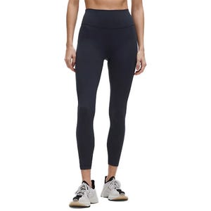 A person is wearing black leggings and athletic shoes. The photograph focuses on the lower half of their body, highlighting the fit and design of the leggings.
