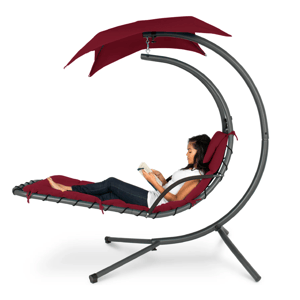 A woman is reading on a hanging lounge chair with a red cushion and canopy, supported by a curved gray frame.