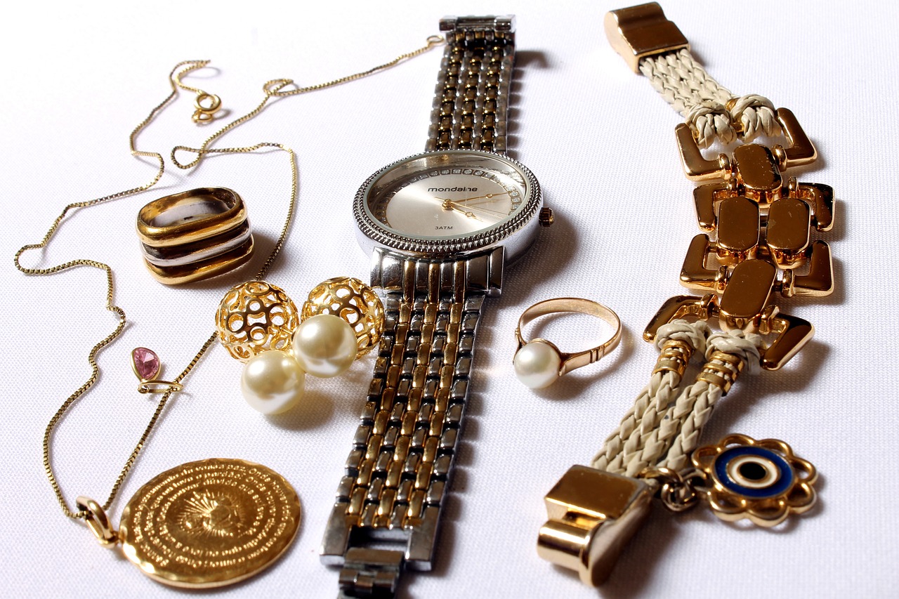 A collection of gold-toned jewelry including a wristwatch, bracelets, earrings, and rings, with pearl and gemstone accents.