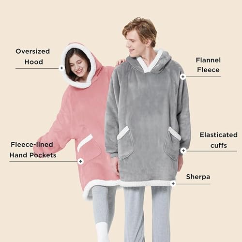 Two people wear oversized hooded fleece blankets, featuring elasticated cuffs, flannel fleece, sherpa lining, and hand pockets.