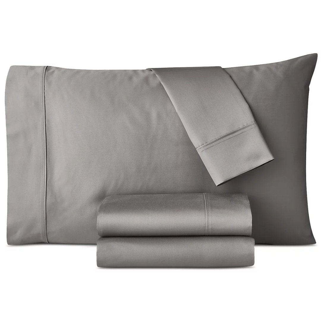 A set of gray bed linens, including a pillowcase, flat sheet, and fitted sheet, is neatly folded and displayed.
