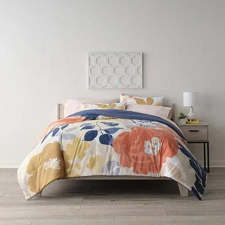 Bed with a floral patterned comforter set in a room with minimalist decor.