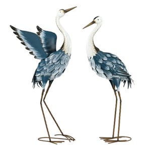 Two metal crane statues with blue and white feather detailing and long, slender legs.