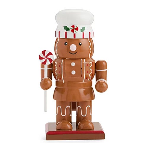 A gingerbread-themed nutcracker with a chef's hat and holding a peppermint candy cane.