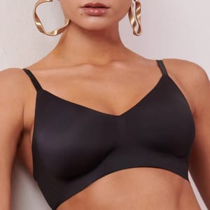 A black wireless bra with wide straps and hoop earrings.