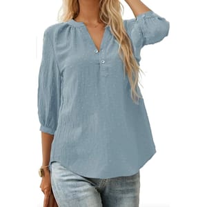 Light blue, long-sleeve blouse with a Swiss dot pattern, featuring a Henley neckline and button detail. Paired with blue jeans.