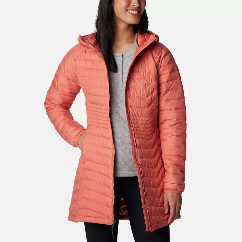 A woman wearing a coral pink hooded puffer jacket and a light grey top.