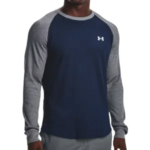 The Under Armour Waffle Crew is a long-sleeve shirt with a navy front and gray heather sleeves, featuring a small Under Armour logo on the chest. It combines a waffle-knit texture for warmth and comfort.