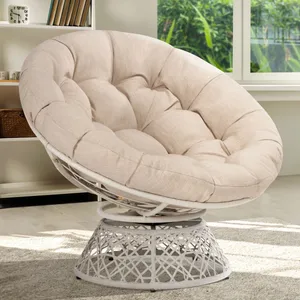 Beige tufted papasan chair with a metal base, placed in a bright room with bookshelves and windows in the background.