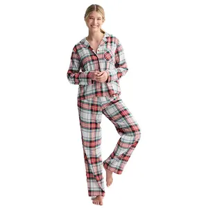 A person wearing a plaid pajama set featuring a button-up long-sleeve top and matching pants with a red, black, and white checker pattern.