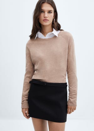 A black mini skirt with a straight cut and a waistband featuring a belt loop and a visible black belt.