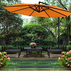 A large orange outdoor umbrella providing shade over a wooden patio set in a garden.