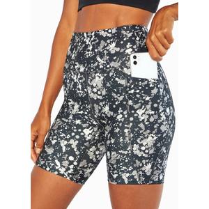 High-waisted athletic shorts with a black and white splatter pattern, featuring a side pocket holding a smartphone.