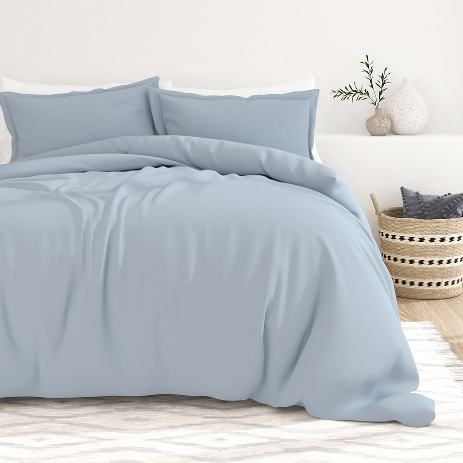 Soft blue double-brushed duvet cover set with a smooth, cozy texture, complemented by matching pillowcases. The setting includes minimalistic decor with a woven basket and vases.