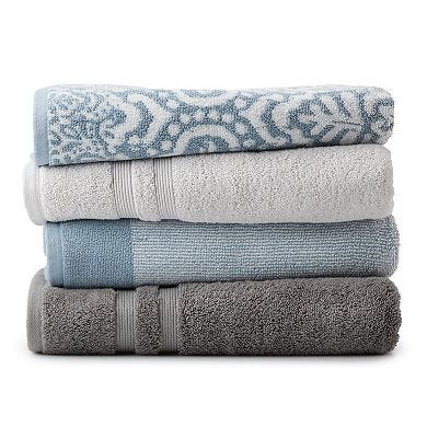 A stack of four plush Sonoma Hygro Bath Towels in a color gradient from light grey to dark grey, with one featuring a blue pattern.