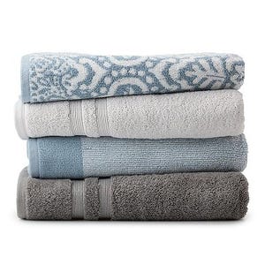 A stack of four plush Sonoma Hygro Bath Towels in a color gradient from light grey to dark grey, with one featuring a blue pattern.
