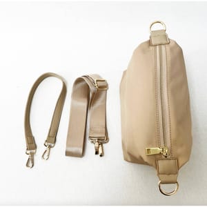 Beige handbag with detachable straps and a gold-tone metal zipper.