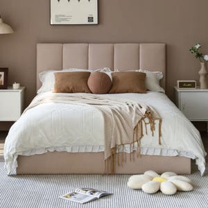 Hydraulic-lift storage bed with a textured headboard in a modern, neutral-toned bedroom featuring white bedding, brown accent pillows, and a decorative throw.