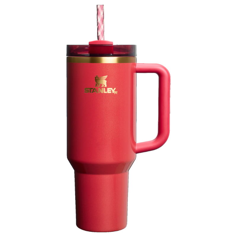 The Stanley Scarlet Tinsel Quencher is a red insulated tumbler with a handle, featuring a lid and straw for easy drinking. The gold Stanley logo is displayed on the side.