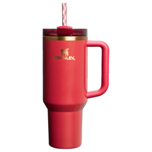 The Stanley Scarlet Tinsel Quencher is a red insulated tumbler with a handle, featuring a lid and straw for easy drinking. The gold Stanley logo is displayed on the side.