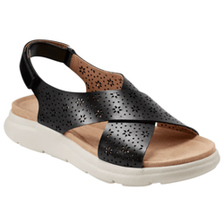 A black sandal with perforated floral patterns on wide straps and a cushioned beige footbed, featuring a white sole and an adjustable back strap.
