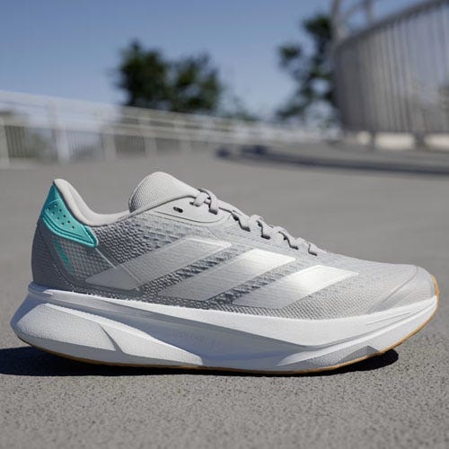 A white and blue Adidas running shoe on a grey road.
