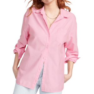 A person is wearing a light pink button-up shirt with rolled-up sleeves, paired with light blue jeans.