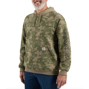 A man wearing a green camouflage hoodie with a logo on the front pocket and lettering running down the sleeve.