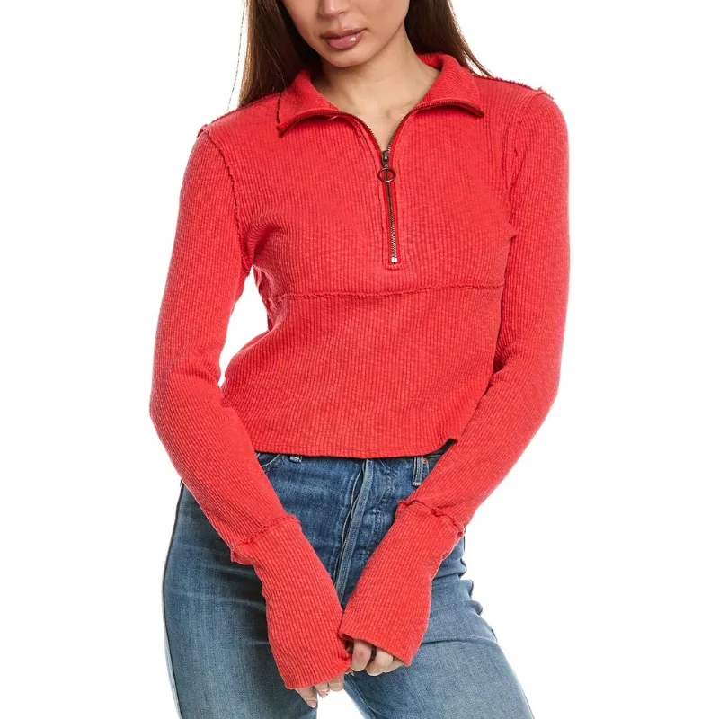 A woman is wearing a textured red quarter-zip long-sleeve top paired with blue jeans.