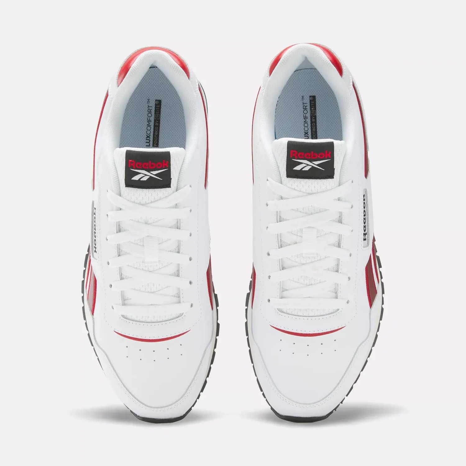 A pair of Reebok Classic Leather shoes in white with red and black accents, featuring a low-cut design and lace-up fronts.