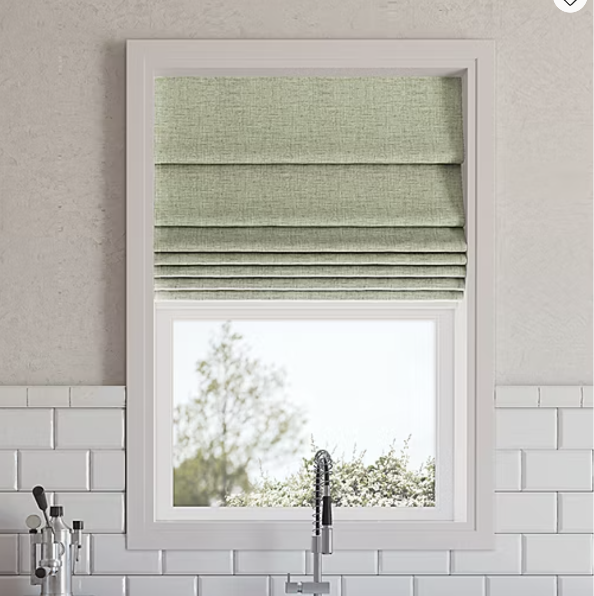 A kitchen window features light green Roman shades partially drawn, above a sleek, modern faucet. The wall is lined with white subway tiles.