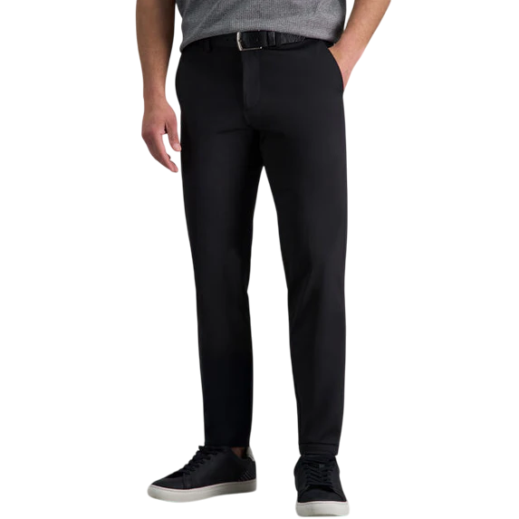 Man wearing slim-fit black pants with a black belt and gray shirt, paired with black sneakers featuring white soles.