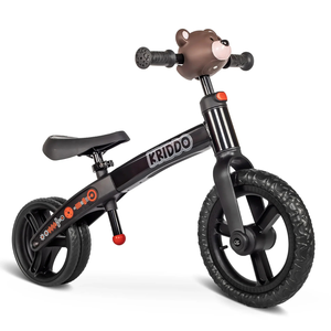 The KRIDDO Dual Balance Bike features a black frame, adjustable seat, and a bear-themed handlebar. It has large black wheels with textured tires for balance and is decorated with orange and white accents.