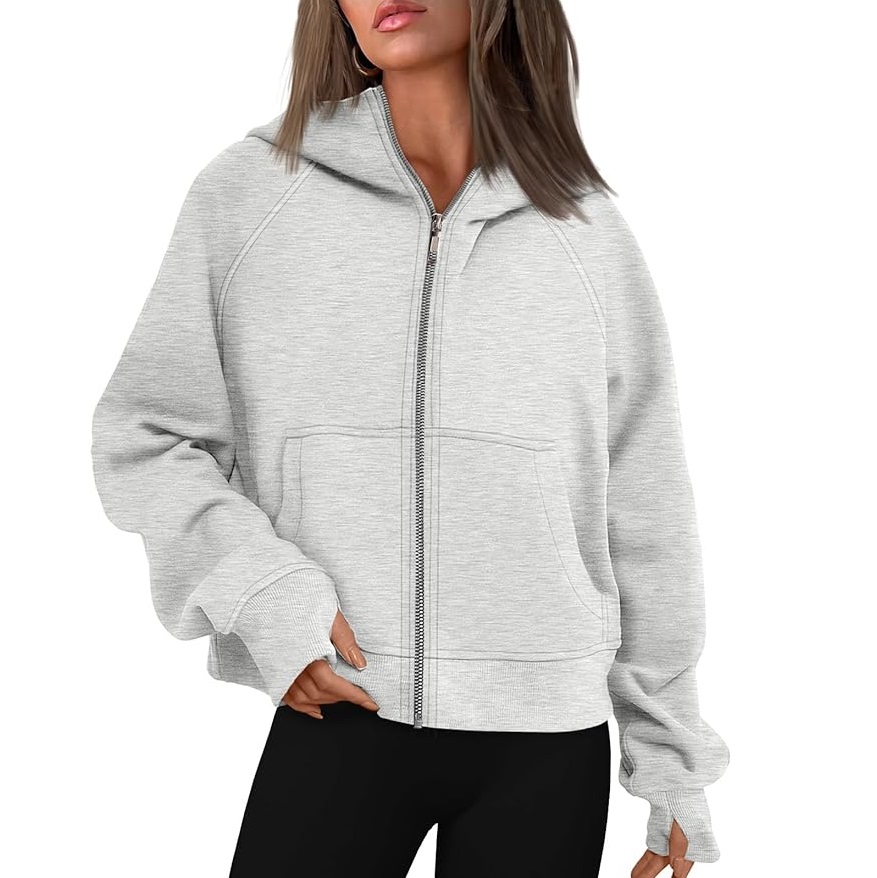 A woman is wearing a gray zip-up hoodie with a hood and front pockets.