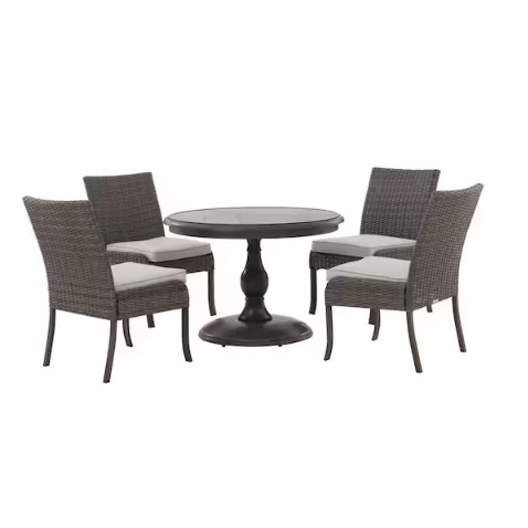 The set includes a round table with a black pedestal base and four wicker-style chairs with cushioned seats, suitable for outdoor dining.