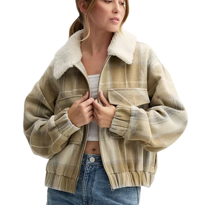 A woman wearing a plaid jacket with a fluffy sherpa collar, white top, and blue jeans. The jacket features elastic cuffs and hem.