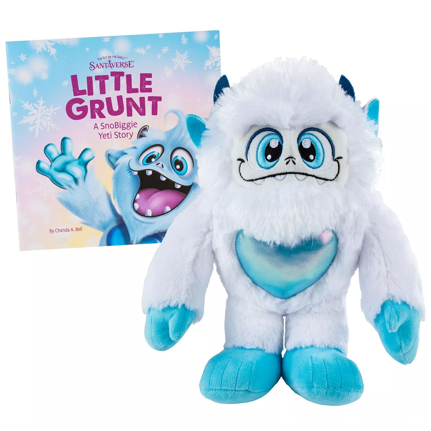 A white and blue plush Yeti with a shimmering heart stands next to a book titled \“Little Grunt: A SnoBiggie Yeti Story\“ by Chanda A. Bell.