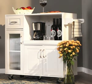 White kitchen cart with a wine rack, towel bar, and storage cabinets next to a vase of flowers.